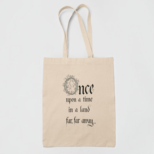 Introducing the "Once Upon a Time Fairytale Tote Bag" from Mirabilia Boutique—a beige tote adorned with the phrase "Once upon a time in a land far, far away..." elegantly scripted in decorative black font. The ornate “O” features an exquisite floral motif, making this enchanting bag an ideal accessory for literary enthusiasts and fairytale fans alike.