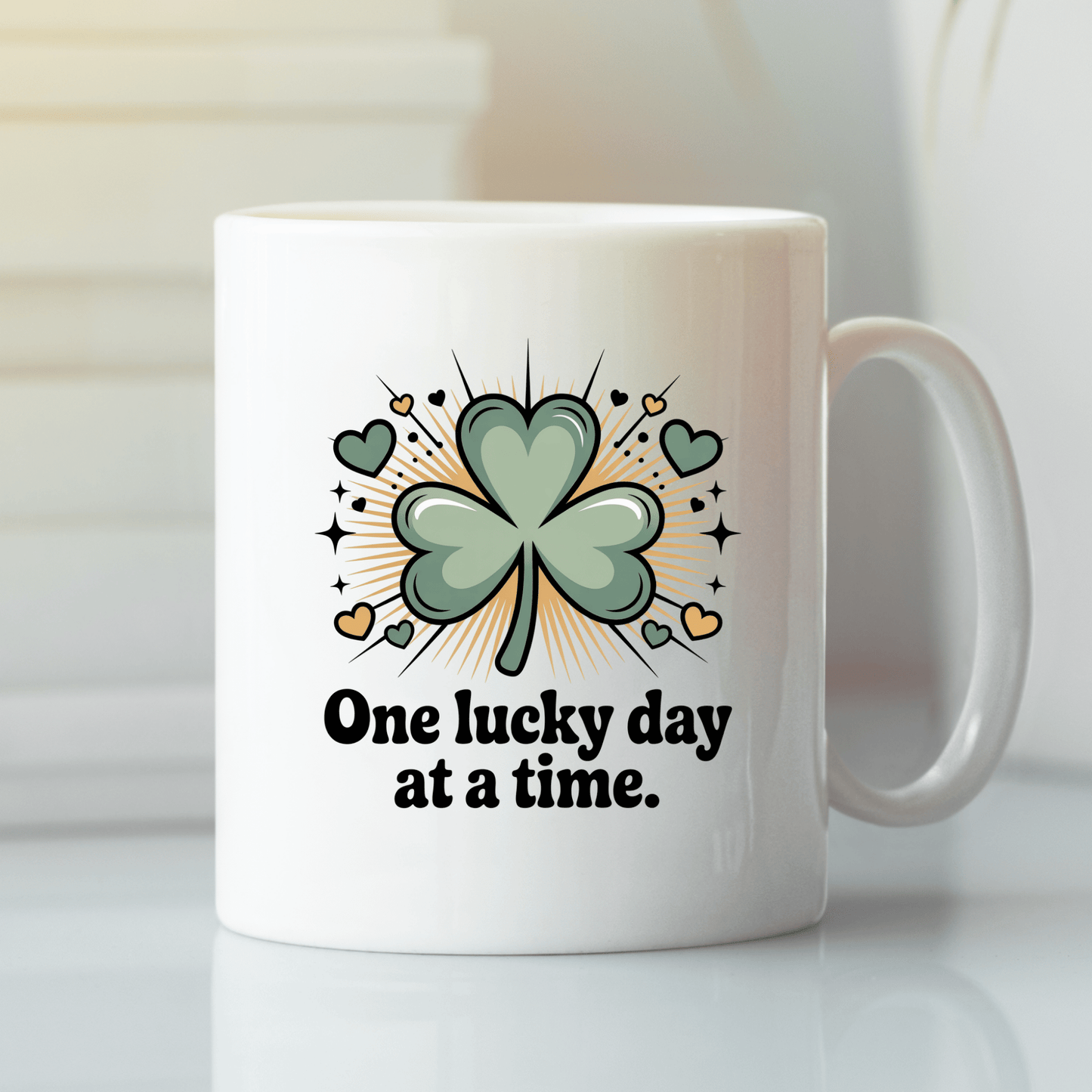 The One Lucky Day at a Time Mug – Shamrock Ceramic Cup by Mirabilia Boutique features a large green shamrock with hearts and rays, plus the phrase “One lucky day at a time”—a charming clover mug for your daily routine.