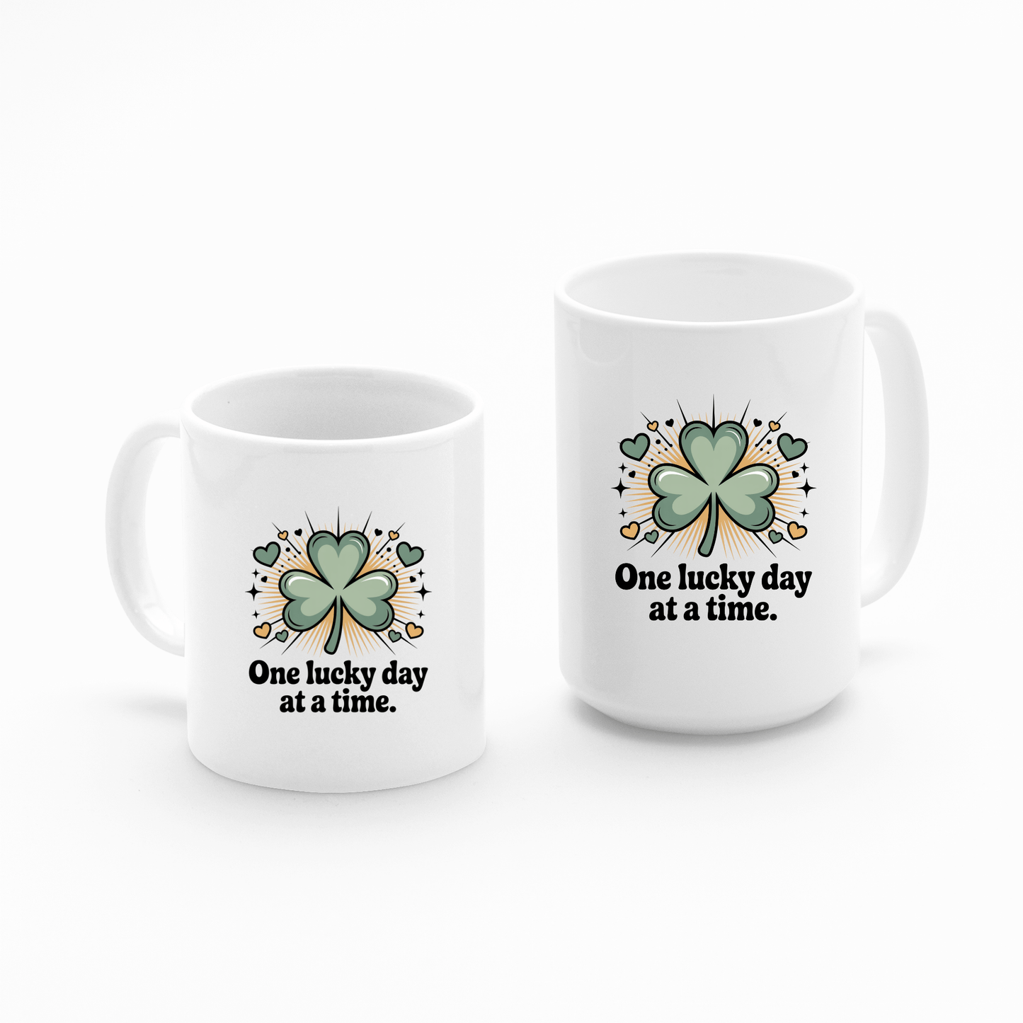 The Mirabilia Boutique "One Lucky Day at a Time Mug – Shamrock Ceramic Cup" features white ceramic, green four-leaf clovers, the uplifting phrase, and is decorated with hearts, stars, and gold coins on each mug.