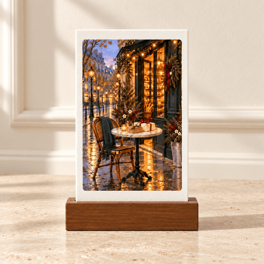 One More Parcel to Carry Home Mini Sign | Paris Toujours rectangular tabletop canvas art in a wooden base, featuring a Parisian cafe exterior at dusk with Christmas wreaths, lights, and a bistro table and chair in the foreground.