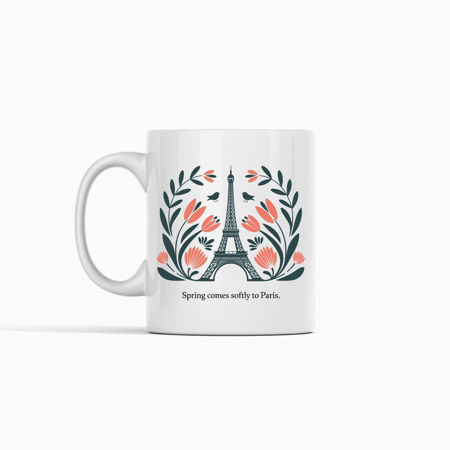 The Paris Spring Mug – Eiffel Tower & Floral Design by Mirabilia Boutique features the Eiffel Tower with pink flowers and green leaves, plus the phrase "Spring comes softly to Paris." A charming ceramic mug for dreamers and travelers.