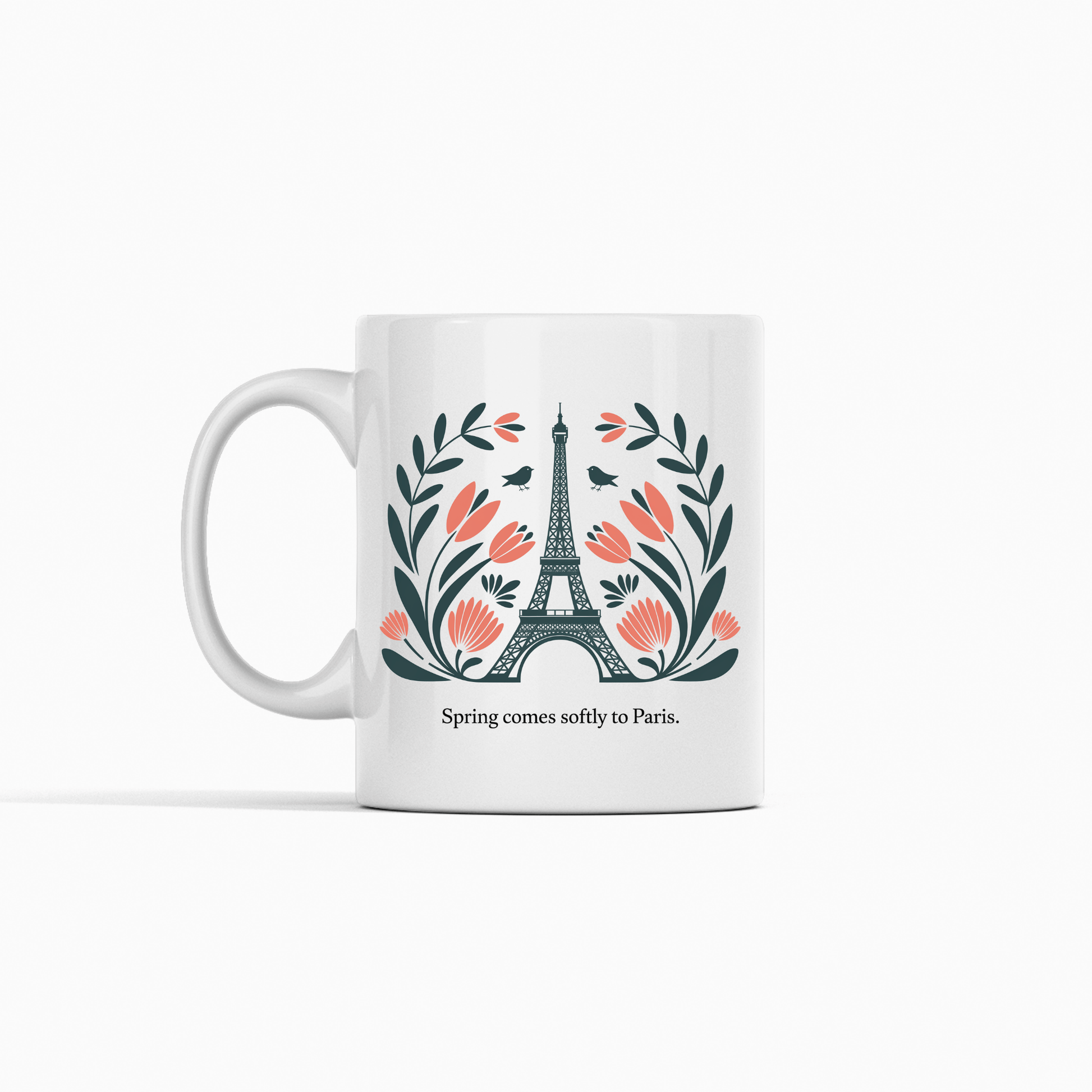The Paris Spring Mug – Eiffel Tower & Floral Design by Mirabilia Boutique features the Eiffel Tower with pink flowers and green leaves, plus the phrase "Spring comes softly to Paris." A charming ceramic mug for dreamers and travelers.