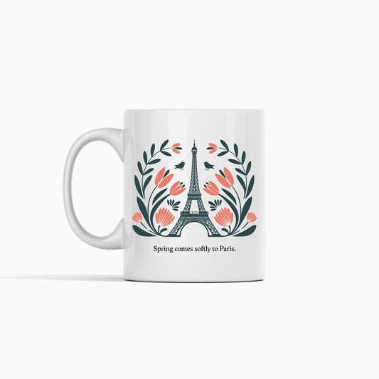 The Paris Spring Mug – Eiffel Tower & Floral Design by Mirabilia Boutique features the Eiffel Tower with pink flowers and green leaves, plus the phrase "Spring comes softly to Paris." A charming ceramic mug for dreamers and travelers.