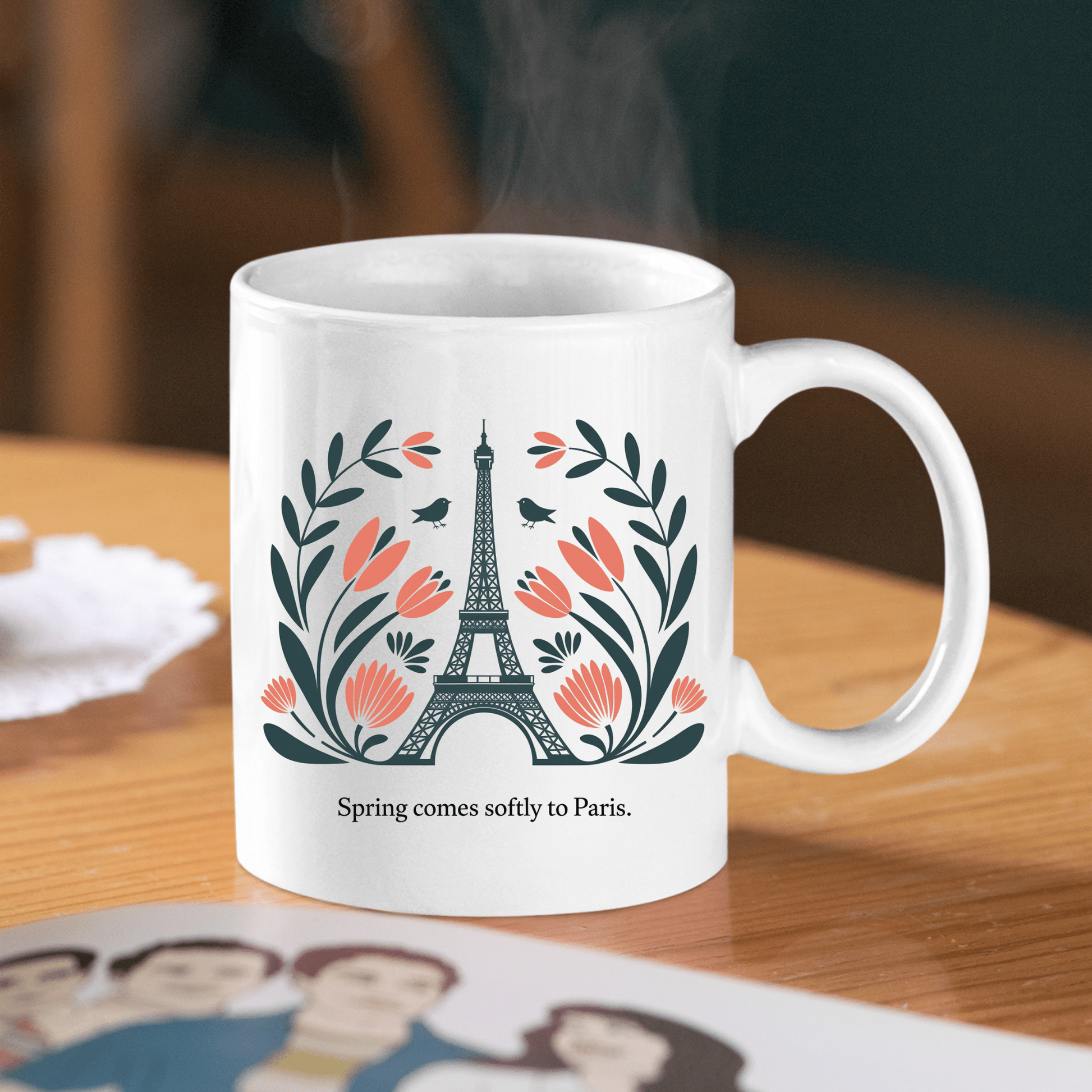 The Mirabilia Boutique Paris Spring Mug features the Eiffel Tower, pink flowers, green leaves, and two birds with the phrase "Spring comes softly to Paris"—a charming ceramic mug perfect for spring.