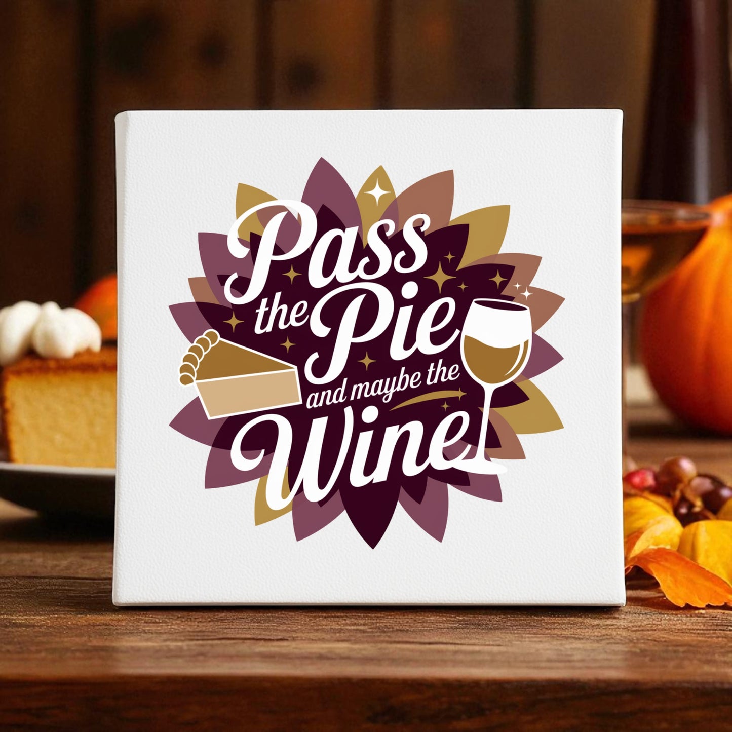 The "Pass the Pie and Maybe the Wine" canvas sign by Mirabilia Boutique features autumn leaves, a pumpkin, and pie—making it fun Thanksgiving decor for cozy fall gatherings.