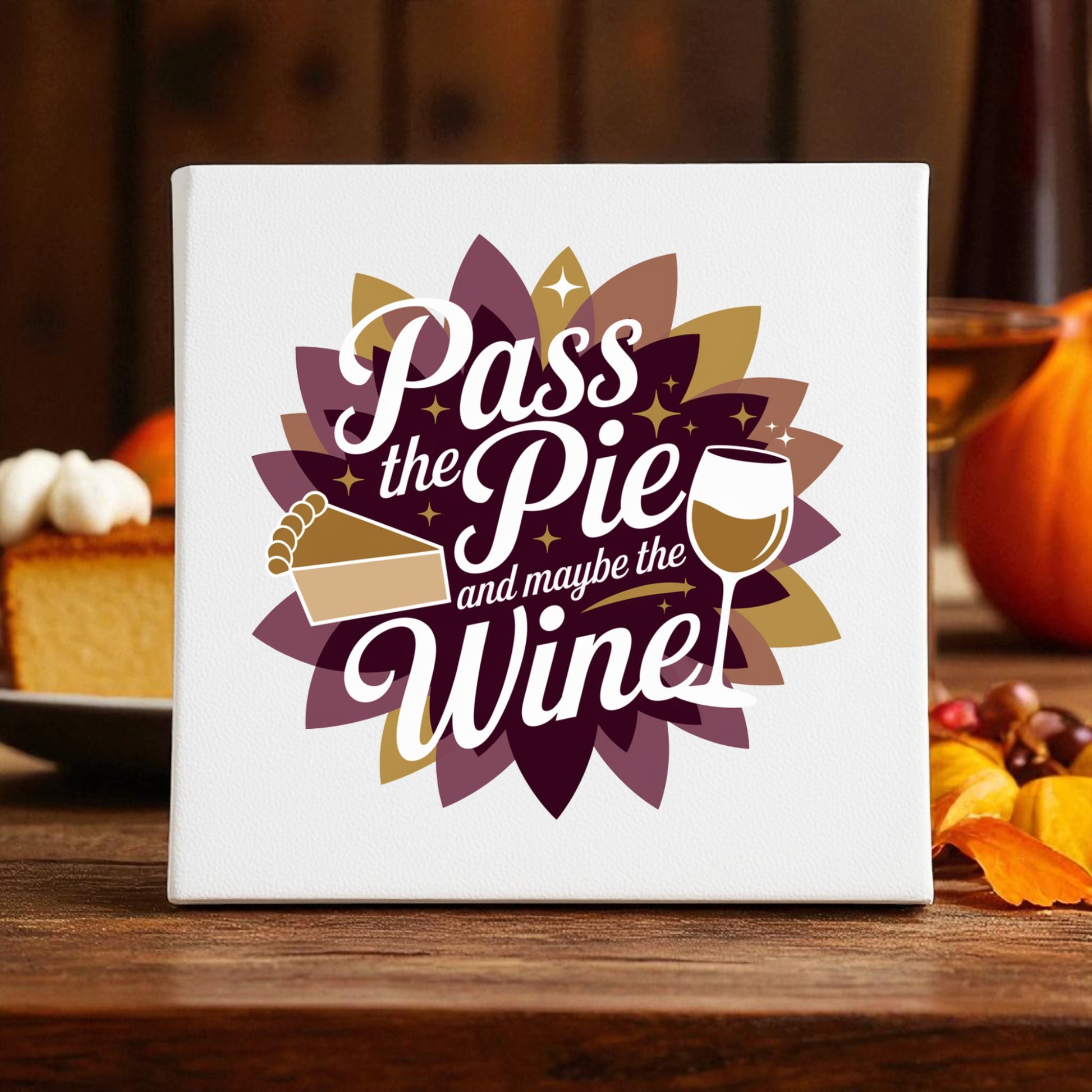 The "Pass the Pie and Maybe the Wine" canvas sign by Mirabilia Boutique features autumn leaves, a pumpkin, and pie—making it fun Thanksgiving decor for cozy fall gatherings.