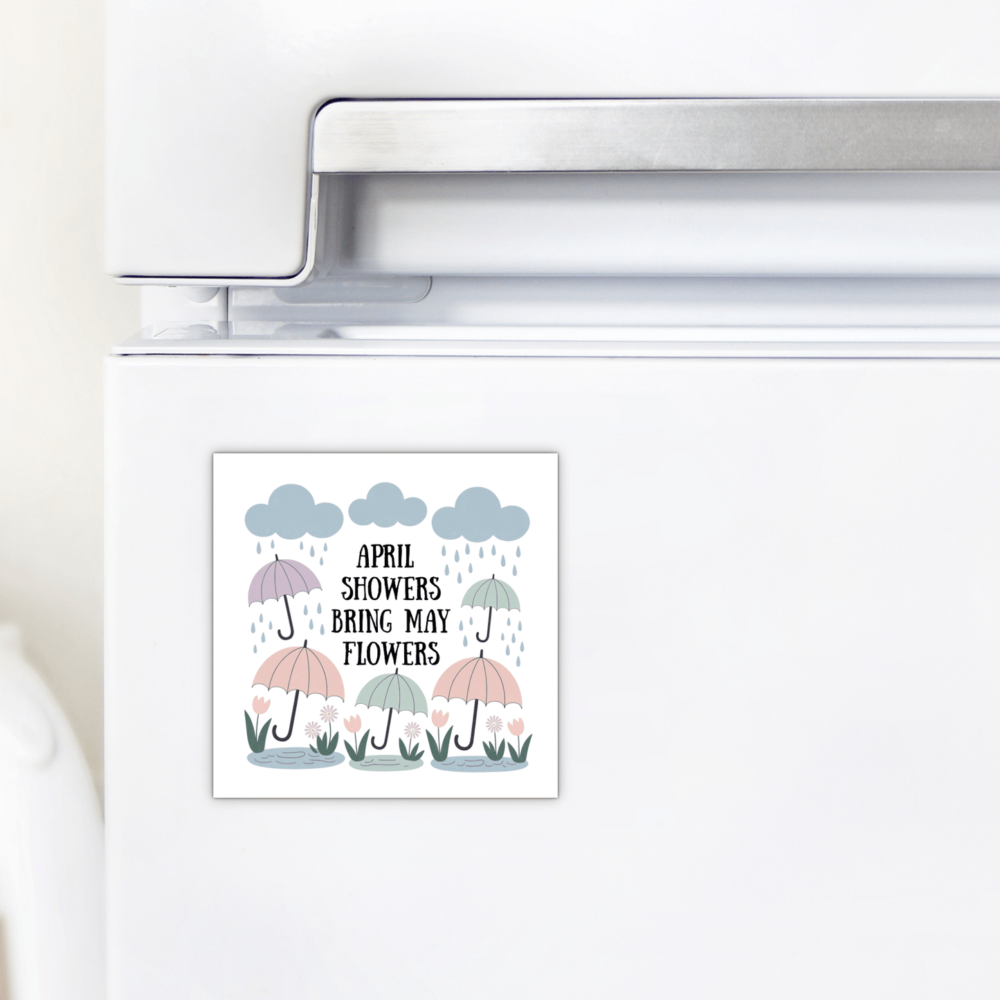 Brighten your kitchen with the Mirabilia Boutique "April Showers Bring May Flowers" Magnet, featuring charming umbrellas, raindrops, clouds, and flowers—the perfect pastel spring accent for your fridge.