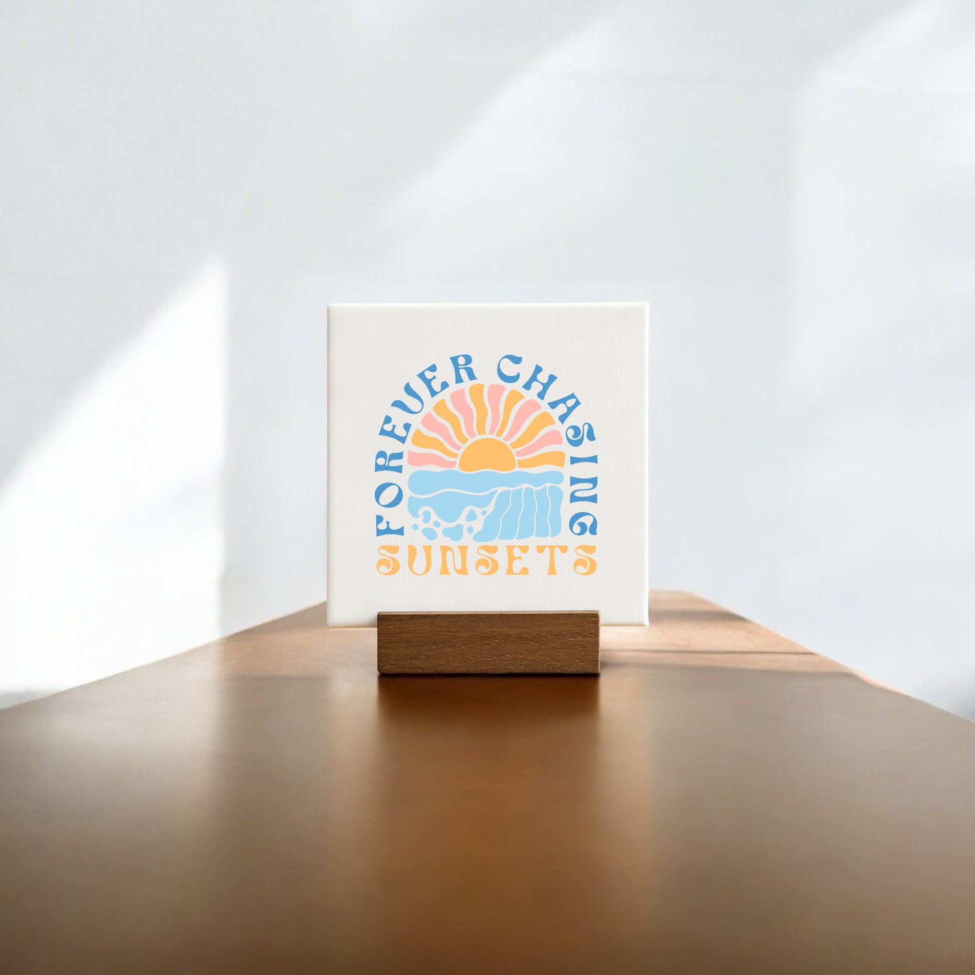 The Forever Chasing Sunsets Mini – Boho Pastel Canvas by Mirabilia Boutique features a sunset illustration with waves and playful blue and orange text, creating charming vintage-inspired wall art for your home.