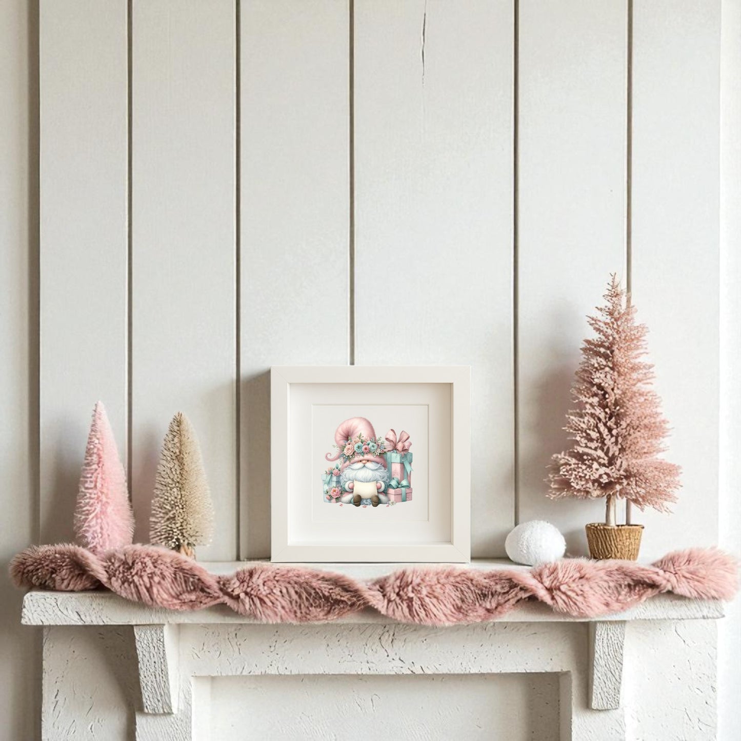 A white mantel adorned with pink and cream bottle brush trees, a textured pink garland, and Mirabilia Boutique’s "Pastel Gnome with Gifts" holiday wall art creates charming holiday decor against a crisp white shiplap wall.