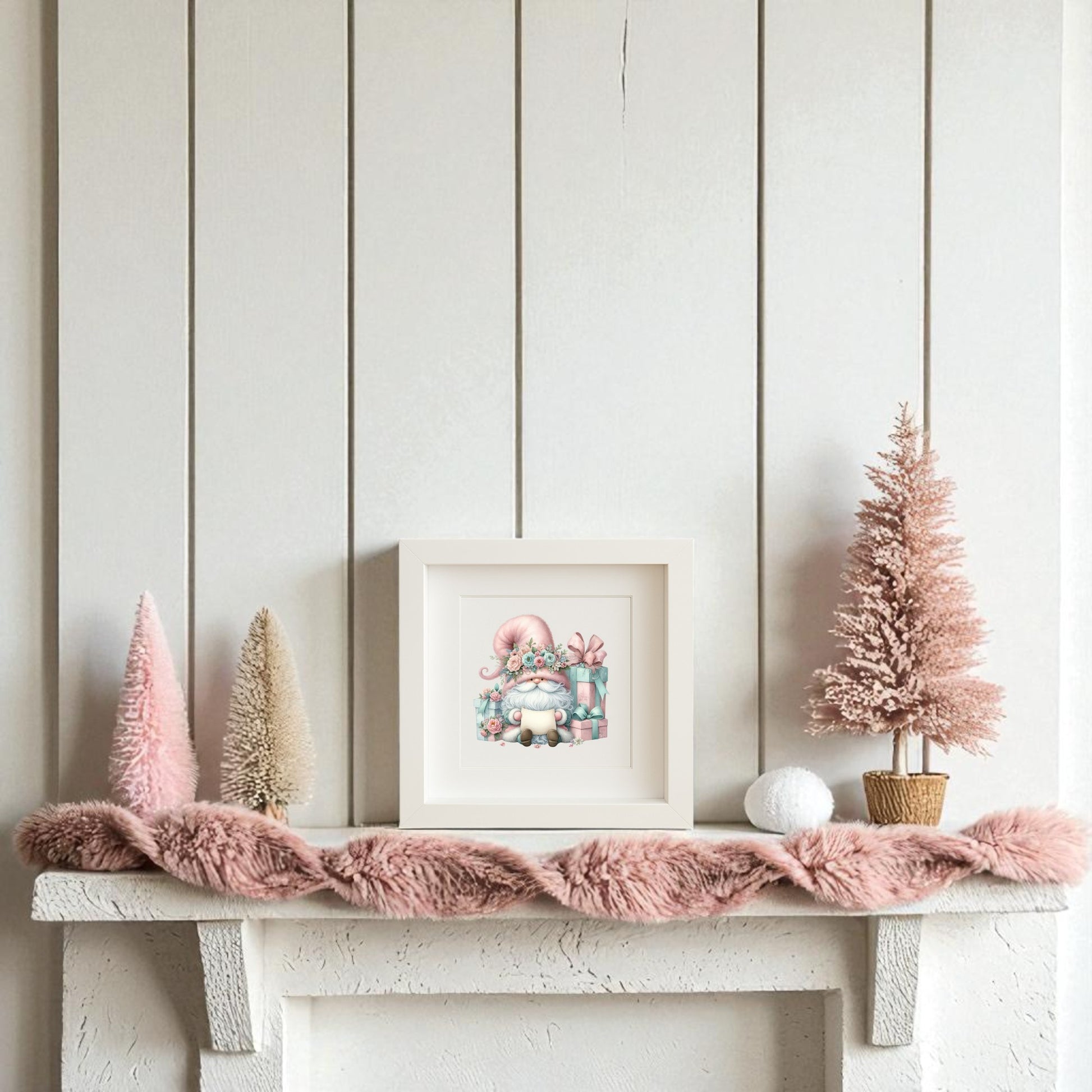 A white mantel adorned with pink and cream bottle brush trees, a textured pink garland, and Mirabilia Boutique’s "Pastel Gnome with Gifts" holiday wall art creates charming holiday decor against a crisp white shiplap wall.