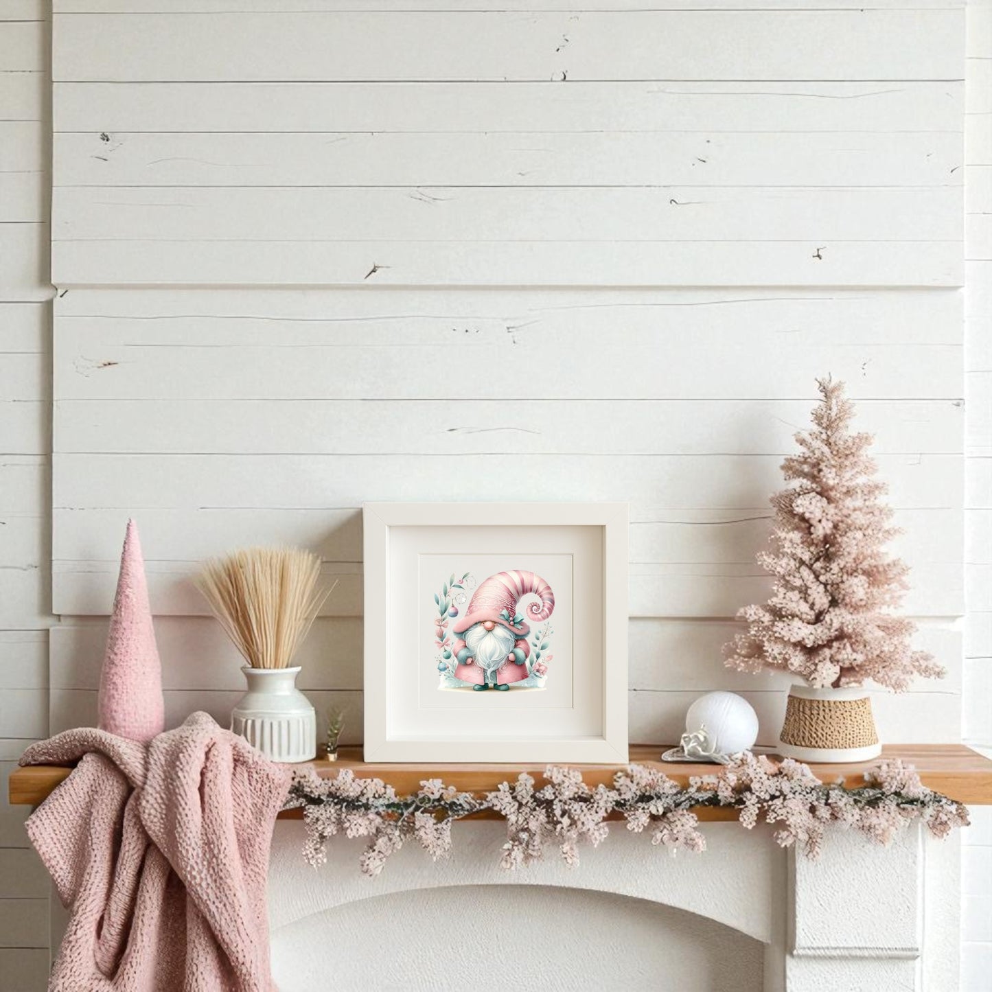A white mantel with a pink knitted blanket, pink tree, vase of wheat, and Mirabilia Boutique’s Pastel Gnome Wall Art creates a cozy Scandinavian-inspired holiday look against a white shiplap wall.