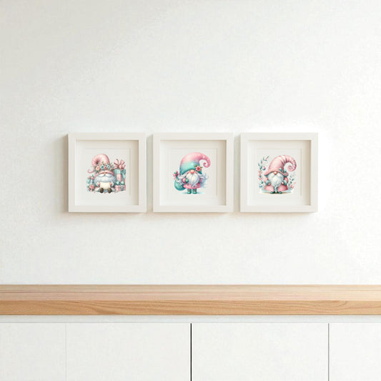 The Pastel Gnome Wall Art Trio by Mirabilia Boutique features three framed prints with pink-hatted gnomes on a clean white wall above a light wood cabinet—perfect for whimsical nursery or winter holiday decor.