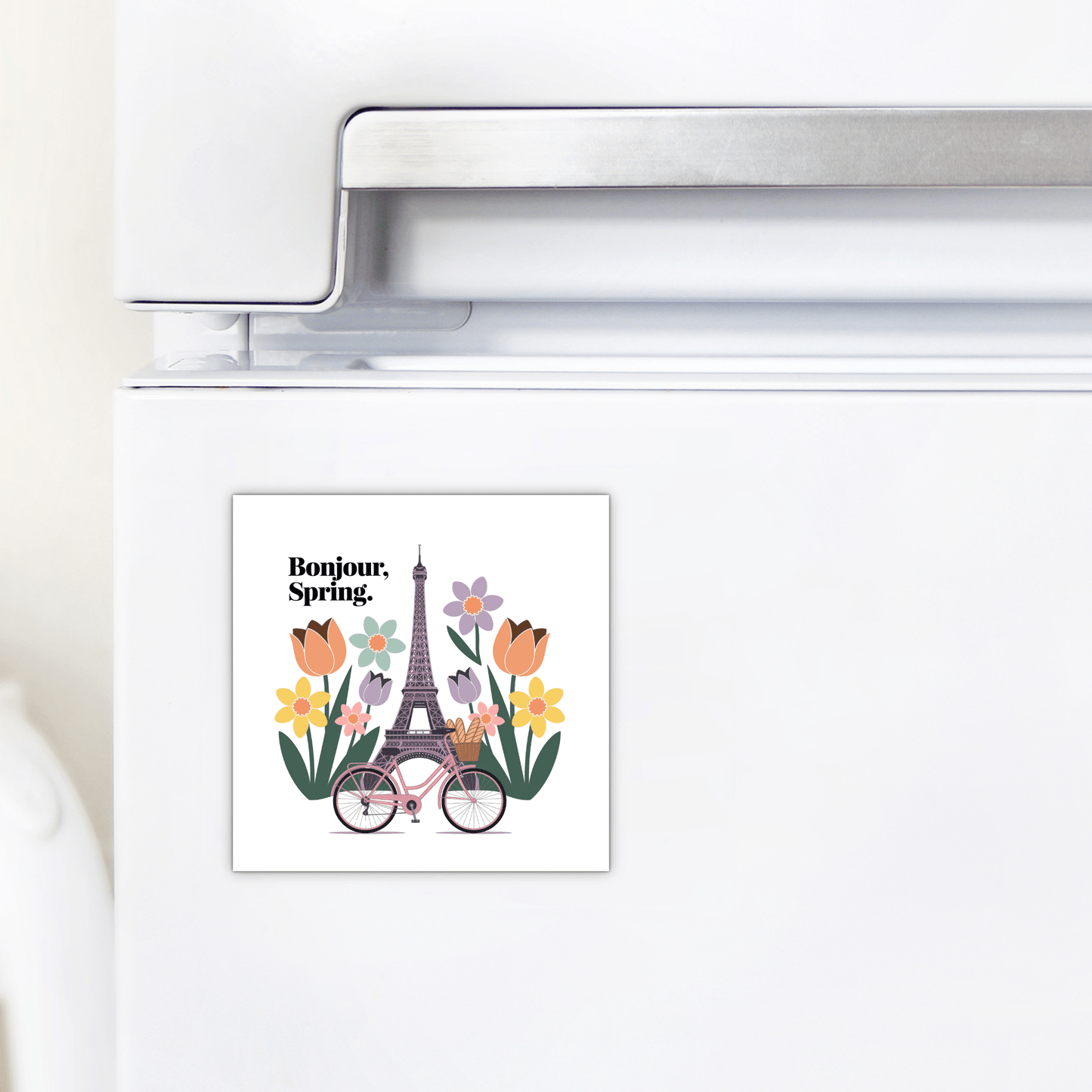 The Bonjour Spring Magnet – Paris Bicycle & Floral Charm by Mirabilia Boutique shows flowers, a pink bicycle, and the Eiffel Tower with "Bonjour, Spring."—a charming Parisian touch for your kitchen fridge.