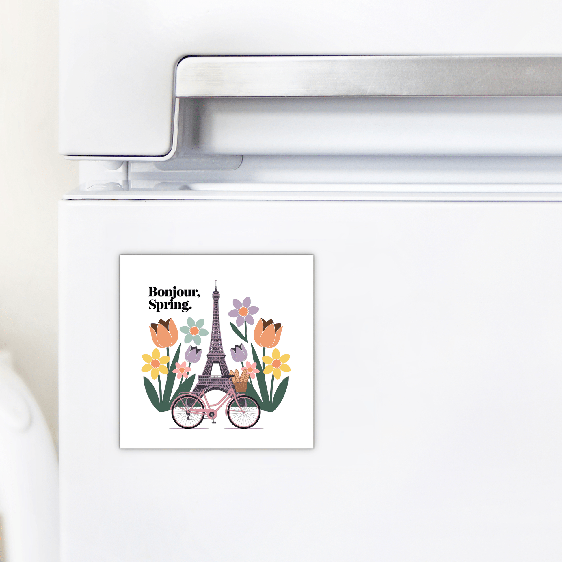The Bonjour Spring Magnet – Paris Bicycle & Floral Charm by Mirabilia Boutique shows flowers, a pink bicycle, and the Eiffel Tower with "Bonjour, Spring."—a charming Parisian touch for your kitchen fridge.