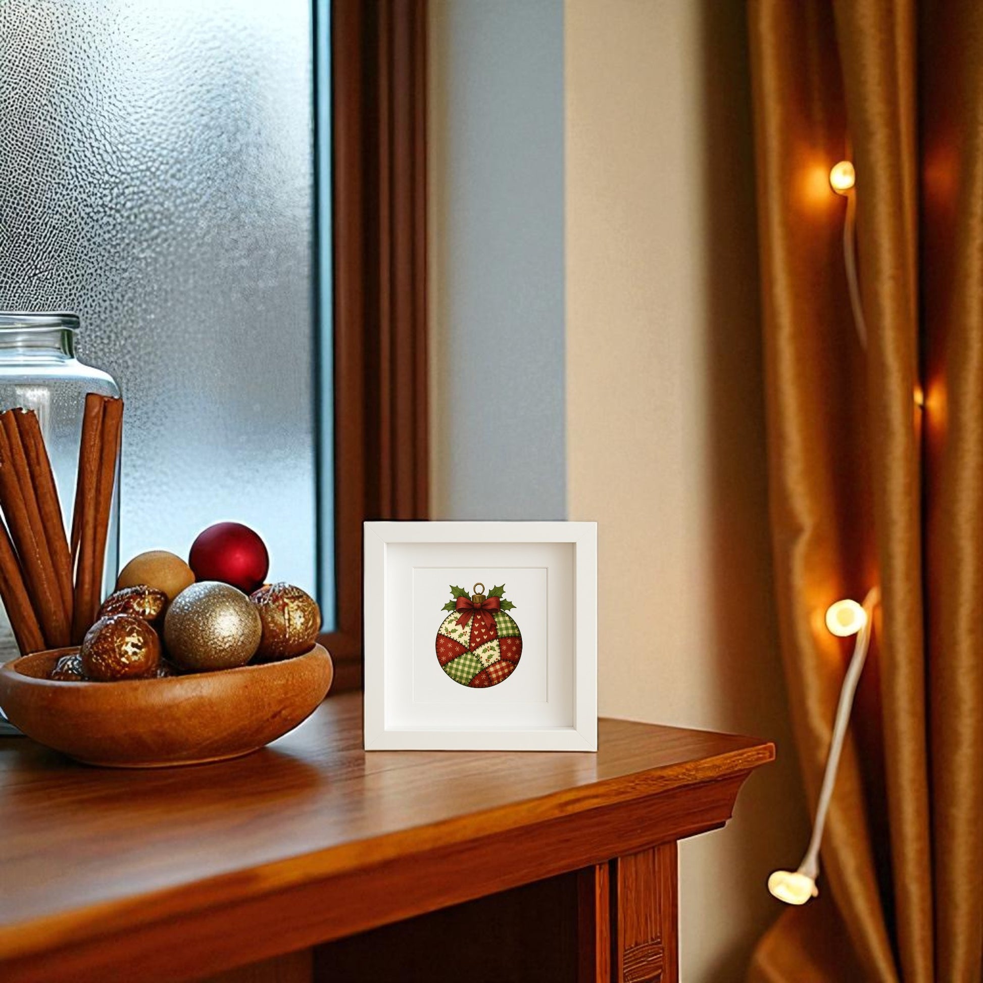 A wooden table holds a bowl of ornaments, cinnamon sticks in a glass jar, and the Mirabilia Boutique Patchwork Ornament Sign (5x5 Christmas Shadowbox Wall Art). Warm string lights and golden curtains by a frosted window complete the farmhouse Christmas décor.