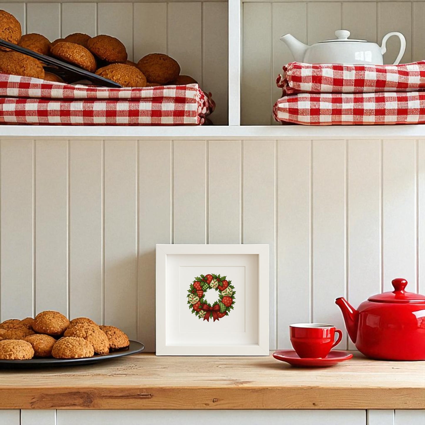 A white kitchen shelf displays baked goods, red-and-white checkered towels, teapots, a red cup and saucer, and the Mirabilia Boutique Patchwork Christmas Wreath Sign | 5x5 Holiday Shadowbox Art for cozy farmhouse holiday decor.