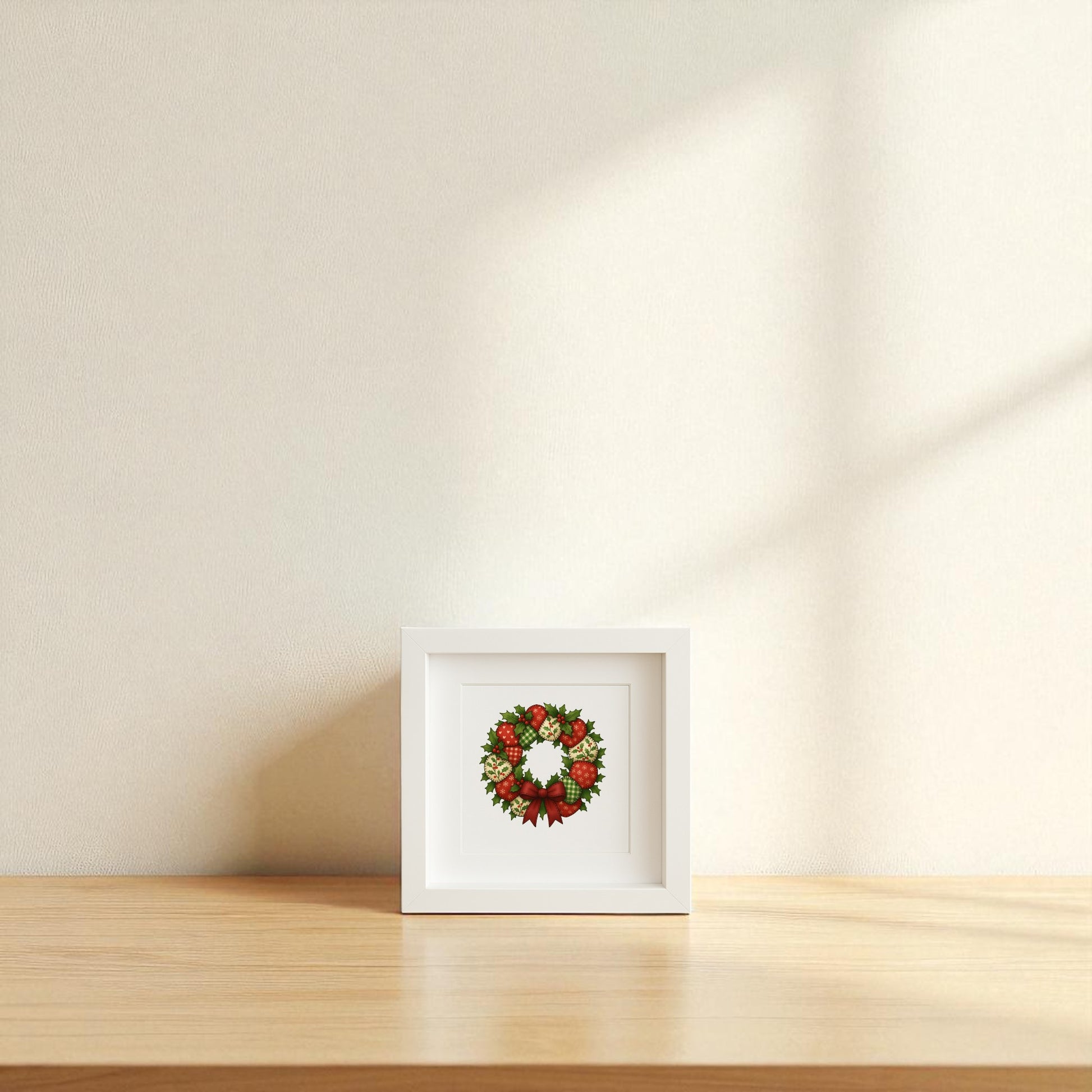 The Patchwork Christmas Wreath Sign | 5x5 Holiday Shadowbox Art by Mirabilia Boutique is displayed on a light wooden surface against a cream wall, sunlight casting soft shadows—a charming piece of farmhouse holiday decor.