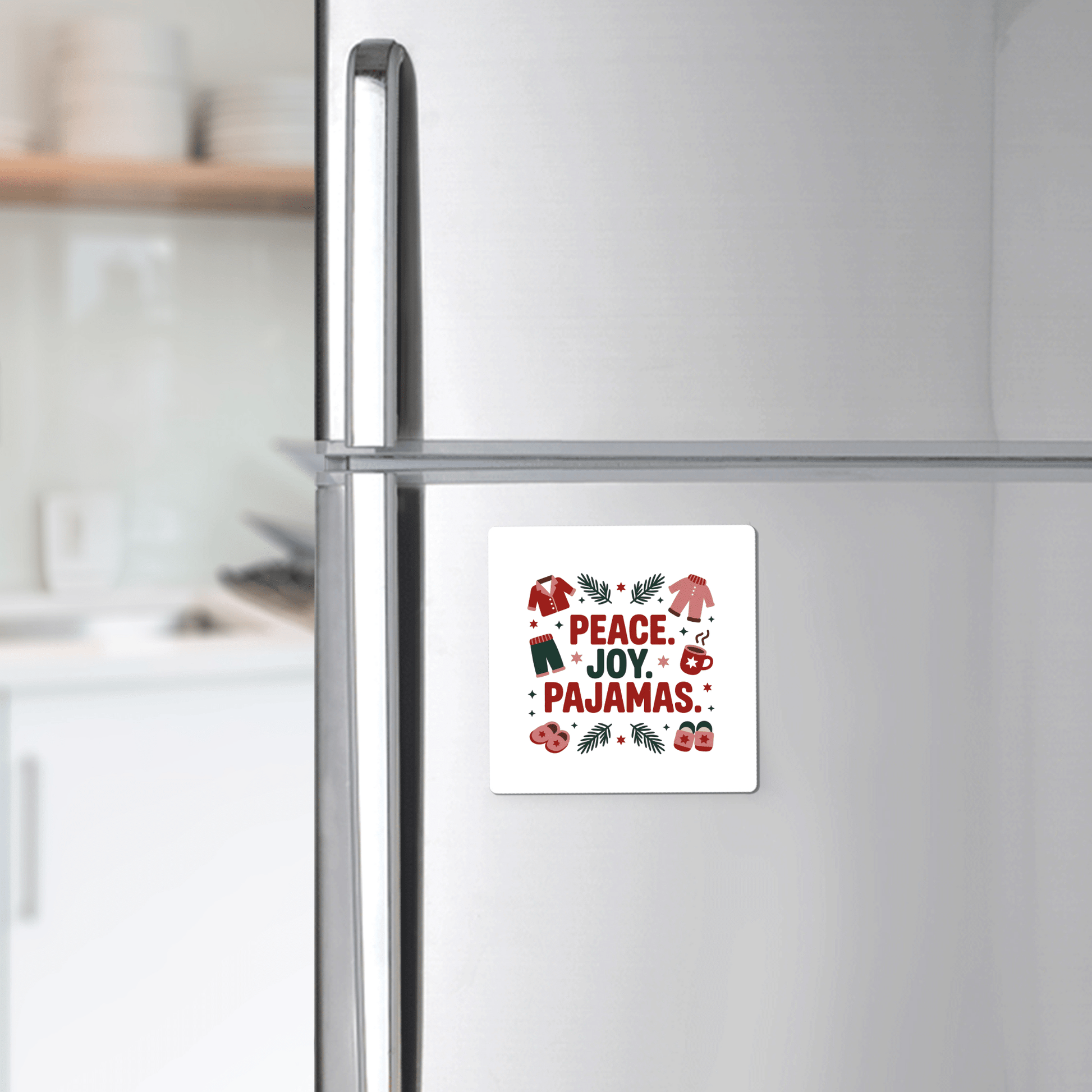 The Peace Joy Pajamas Magnet by Mirabilia Boutique adds cheer to a stainless steel fridge, featuring the festive message "Peace. Joy. Pajamas." for a cozy holiday touch to your kitchen décor.