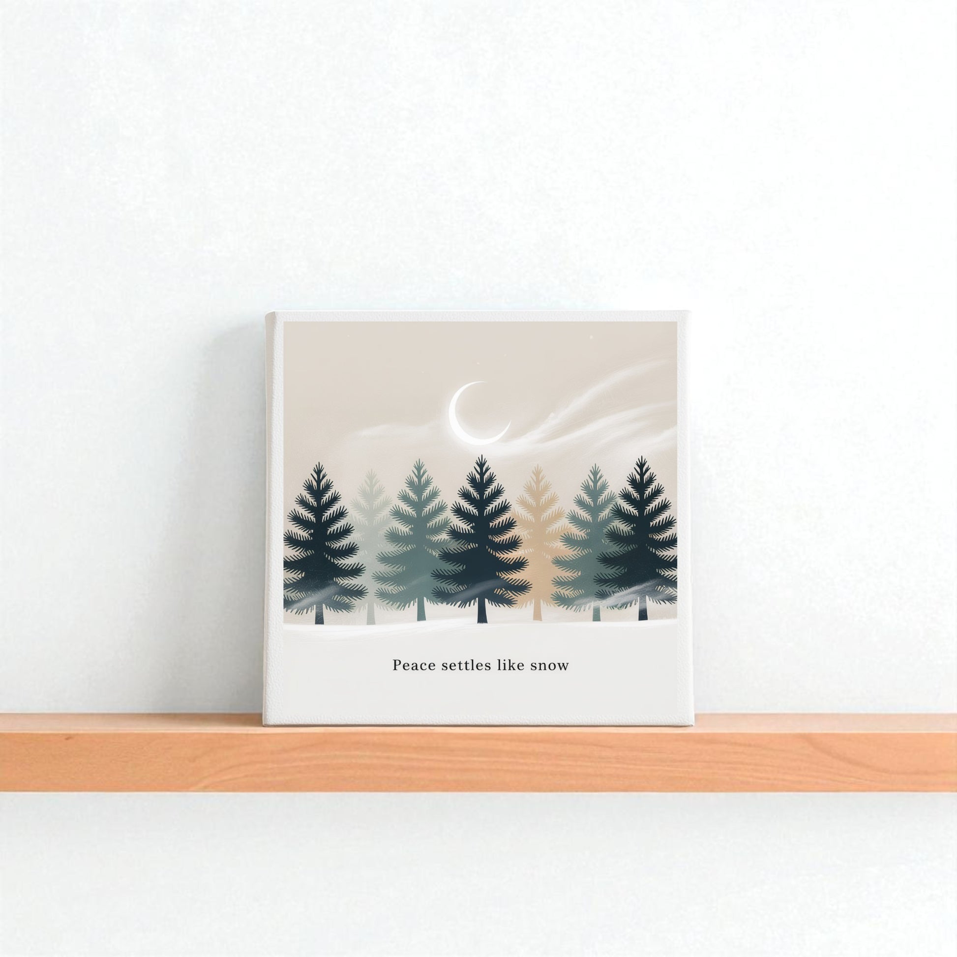 The Peace Settles Like Snow Canvas by Mirabilia Boutique features illustrated pine trees beneath a crescent moon and mist with the phrase “Peace settles like snow”—a serene winter minimalist wall art for any nursery or room.