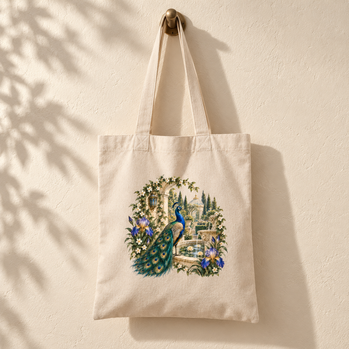 Afternoon in the Peacock Garden Tote | Gilded Reverie by Mirabilia Boutique hangs on the wall, showcasing a printed design of a jeweled peacock beside a fountain, surrounded by lush greenery and purple flowers—a stunning botanical tote bag that adds everyday elegance to any ensemble.