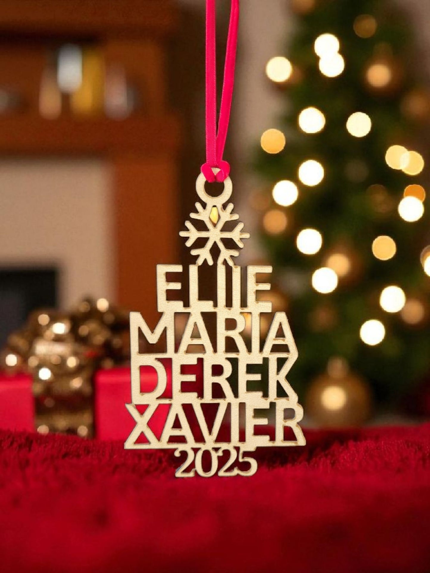 The Mirabilia Boutique Custom Family Christmas Ornament With Year features the names Ellie, Maria, Derek, Xavier, and 2025 on wood. This personalized holiday decor hangs by a red ribbon, making it a charming keepsake for your festive tree.
