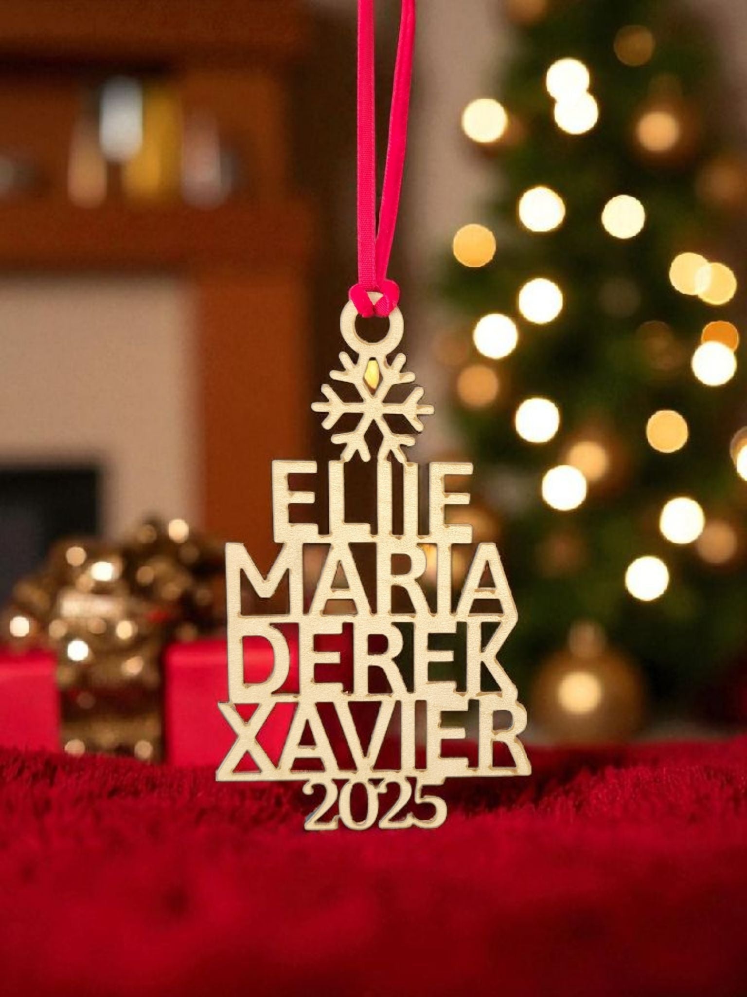 The Mirabilia Boutique Custom Family Christmas Ornament With Year features the names Ellie, Maria, Derek, Xavier, and 2025 on wood. This personalized holiday decor hangs by a red ribbon, making it a charming keepsake for your festive tree.