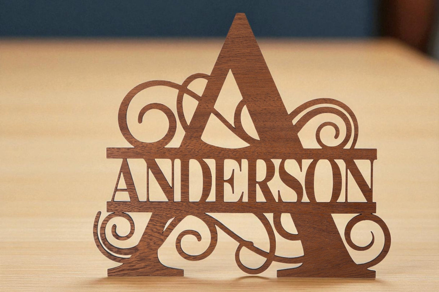 The Custom Walnut Name Cutout by Mirabilia Boutique showcases a large decorative "A" with "ANDERSON" cut out, creating a stunning personalized decor gift on a light wood surface.
