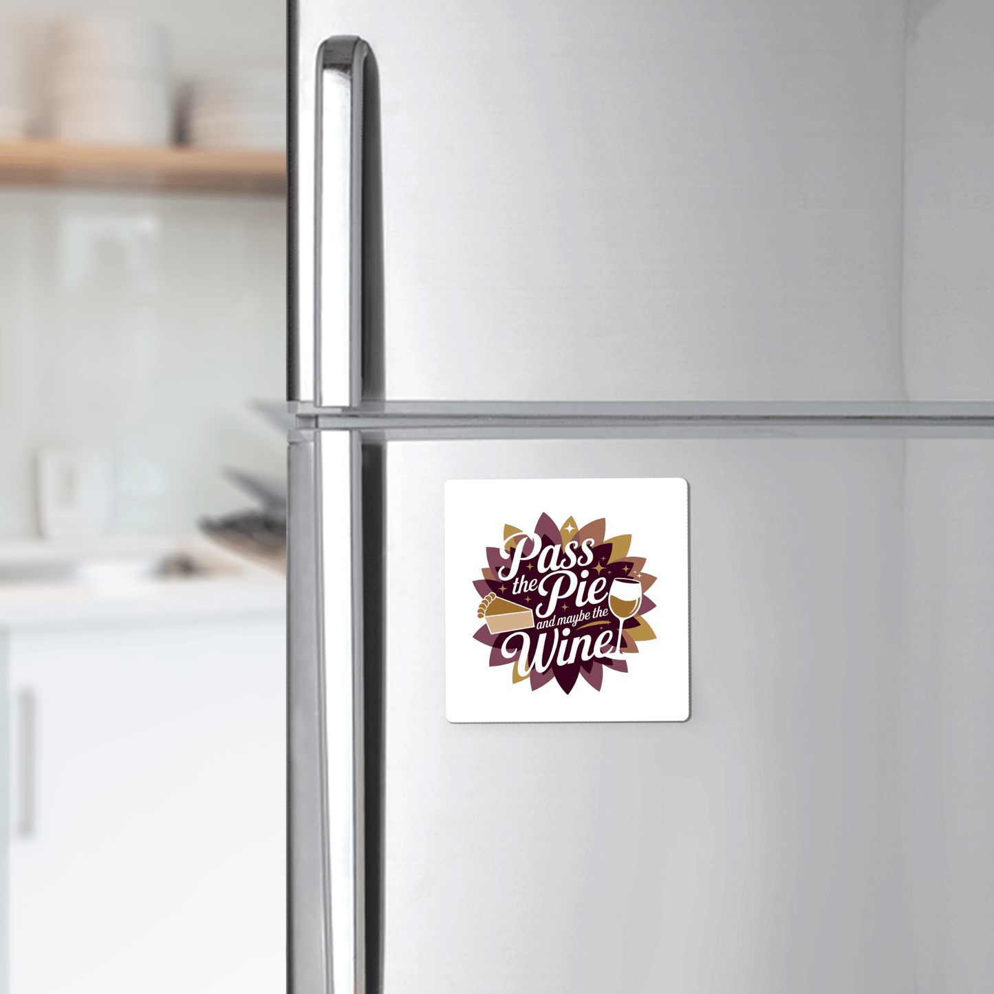 A stainless steel fridge with the Mirabilia Boutique "Pass the Pie & Wine Magnet"—a funny Thanksgiving fridge decor, perfect as a wine lover gift or festive holiday kitchen accent—displayed among white shelves and dishes.