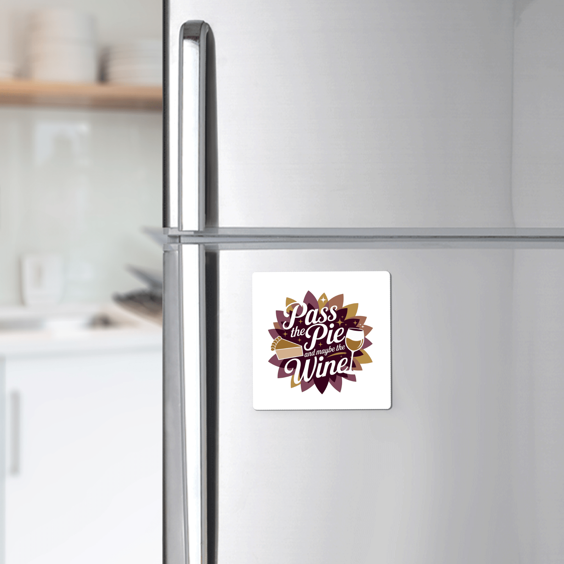 A stainless steel fridge with the Mirabilia Boutique "Pass the Pie & Wine Magnet"—a funny Thanksgiving fridge decor, perfect as a wine lover gift or festive holiday kitchen accent—displayed among white shelves and dishes.