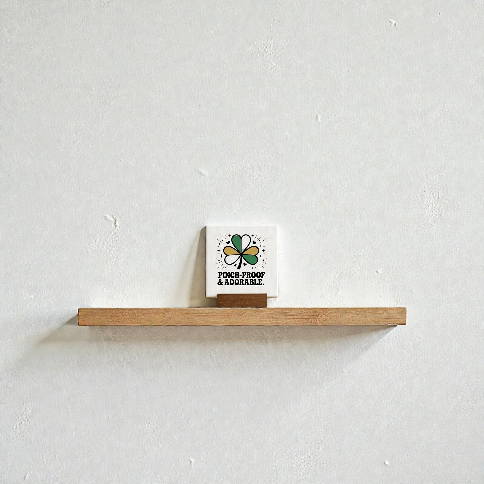 A small wooden shelf displays the Mirabilia Boutique Pinch-Proof & Adorable Canvas Sign (4x4), featuring a green shamrock and festive text—an adorable St. Patrick’s Day decor accent for any kids room.