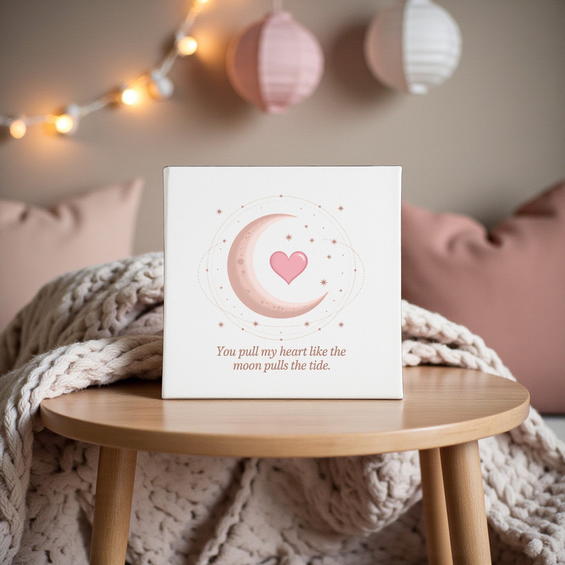 The Moon Pulls the Tide Love Quote Canvas by Mirabilia Boutique features the moon, stars, and a pink heart, with the words, "You pull my heart like the moon pulls the tide," creating a romantic scene perfect for celestial home decor.