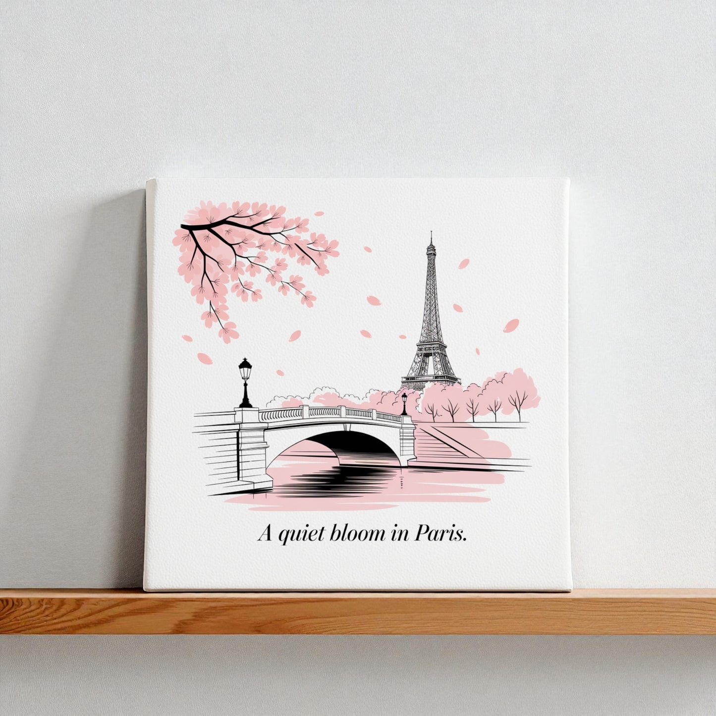The Quiet Bloom in Paris Canvas – Cherry Blossom Spring Art by Mirabilia Boutique features the Eiffel Tower, bridge, and pink petals with "A quiet bloom in Paris"—perfect wall art for any room.