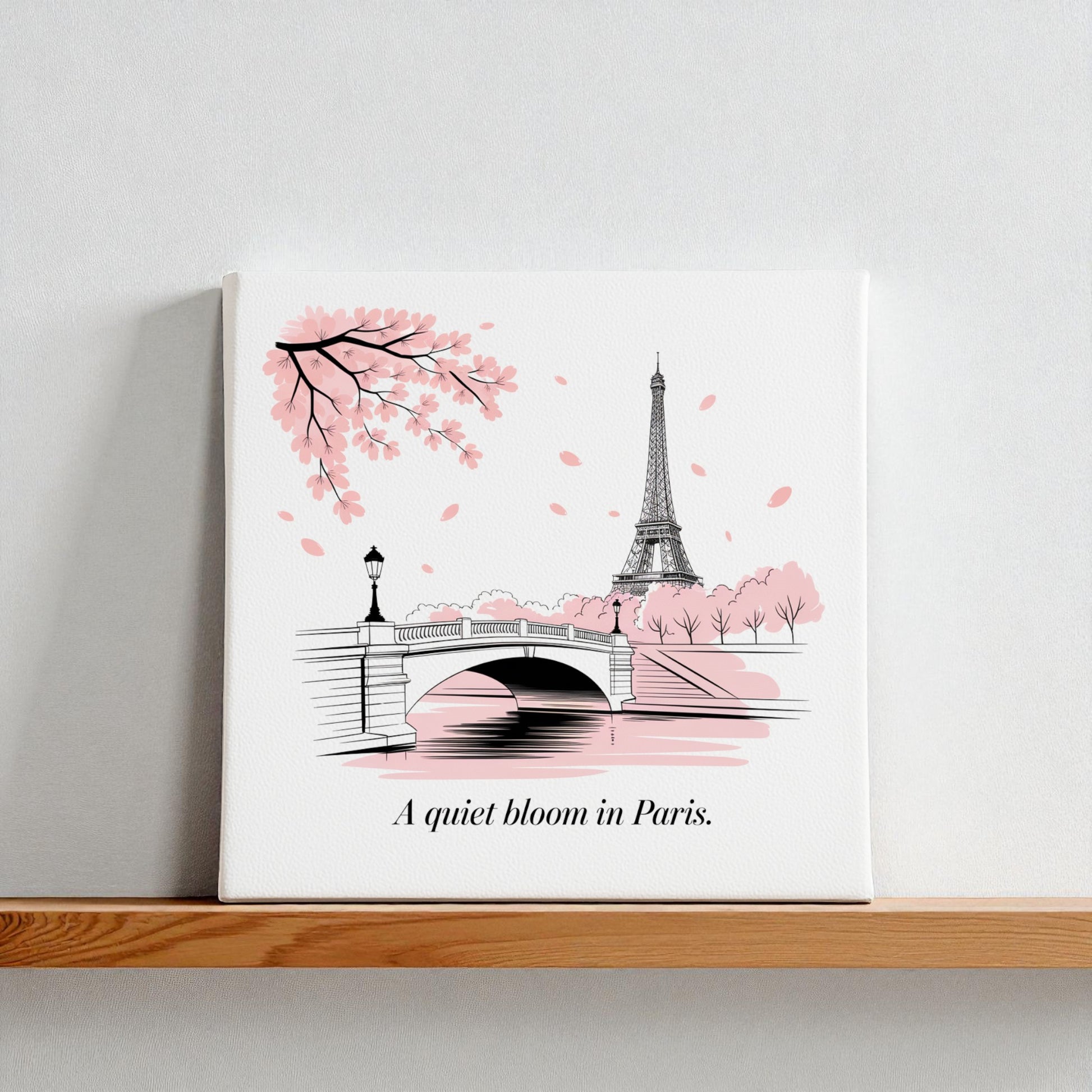 The Quiet Bloom in Paris Canvas – Cherry Blossom Spring Art by Mirabilia Boutique features the Eiffel Tower, bridge, and pink petals with "A quiet bloom in Paris"—perfect wall art for any room.