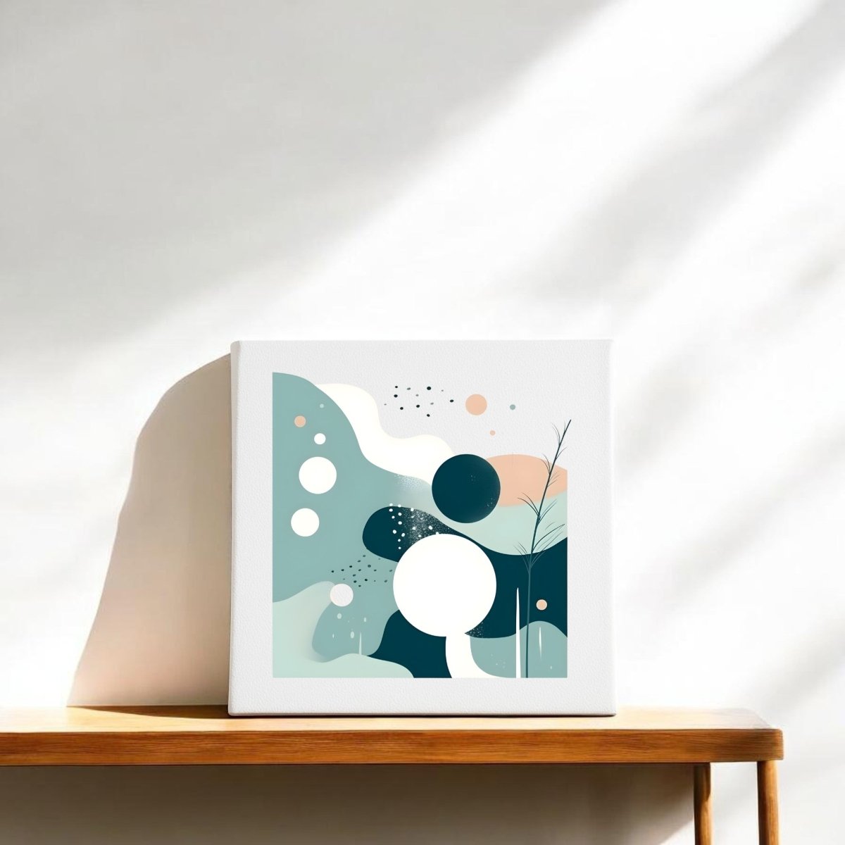 The Quiet Tides Mid Century Modern Canvas by Mirabilia Boutique features minimalist geometric shapes in soft colors, displayed on a wooden shelf against a white wall, elegantly illuminated by natural sunlight.