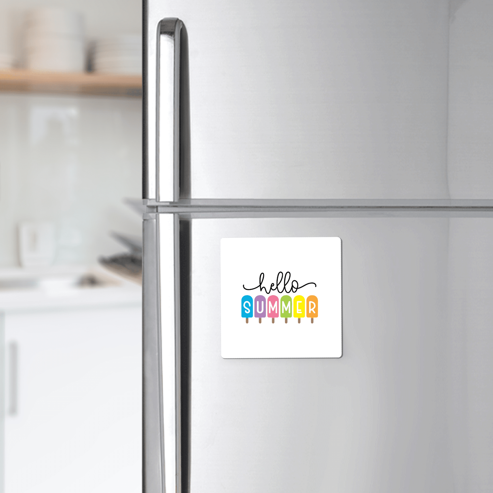 The Hello Summer Popsicle Magnet – Rainbow Ice Pop Fridge Art by Mirabilia Boutique brings a cheerful touch to the silver refrigerator.