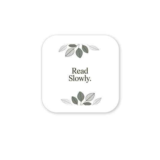 The Read Slowly Book Lover Magnet by Mirabilia Boutique features a white square with rounded corners, "Read Slowly." text in the center, and green and gray leaf illustrations—a stylish literary gift or decor for any book lover.