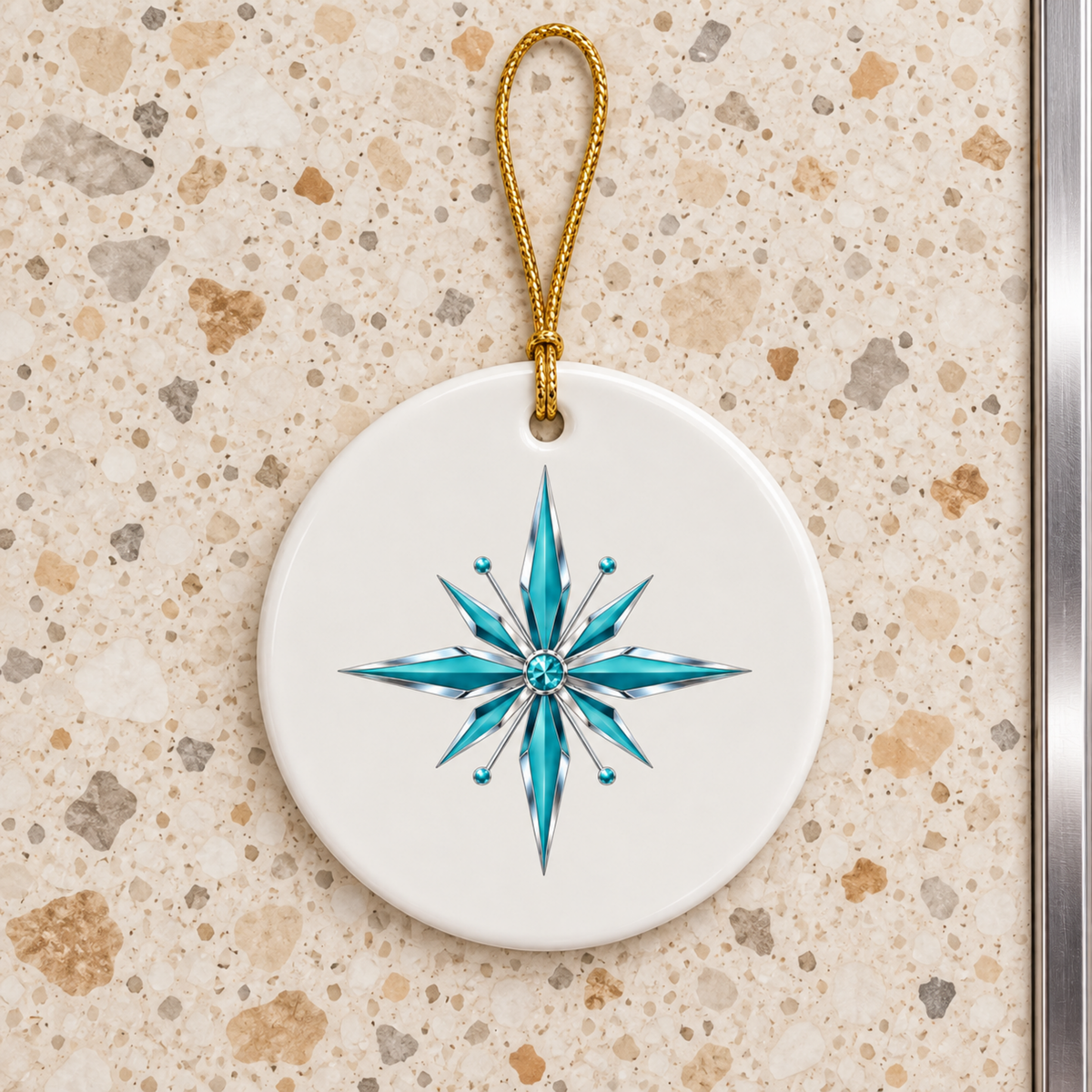 Starlite Starburst Ceramic Ornament is a circular white ceramic Christmas ornament with a blue and silver turquoise starburst design and a gold hanging loop.