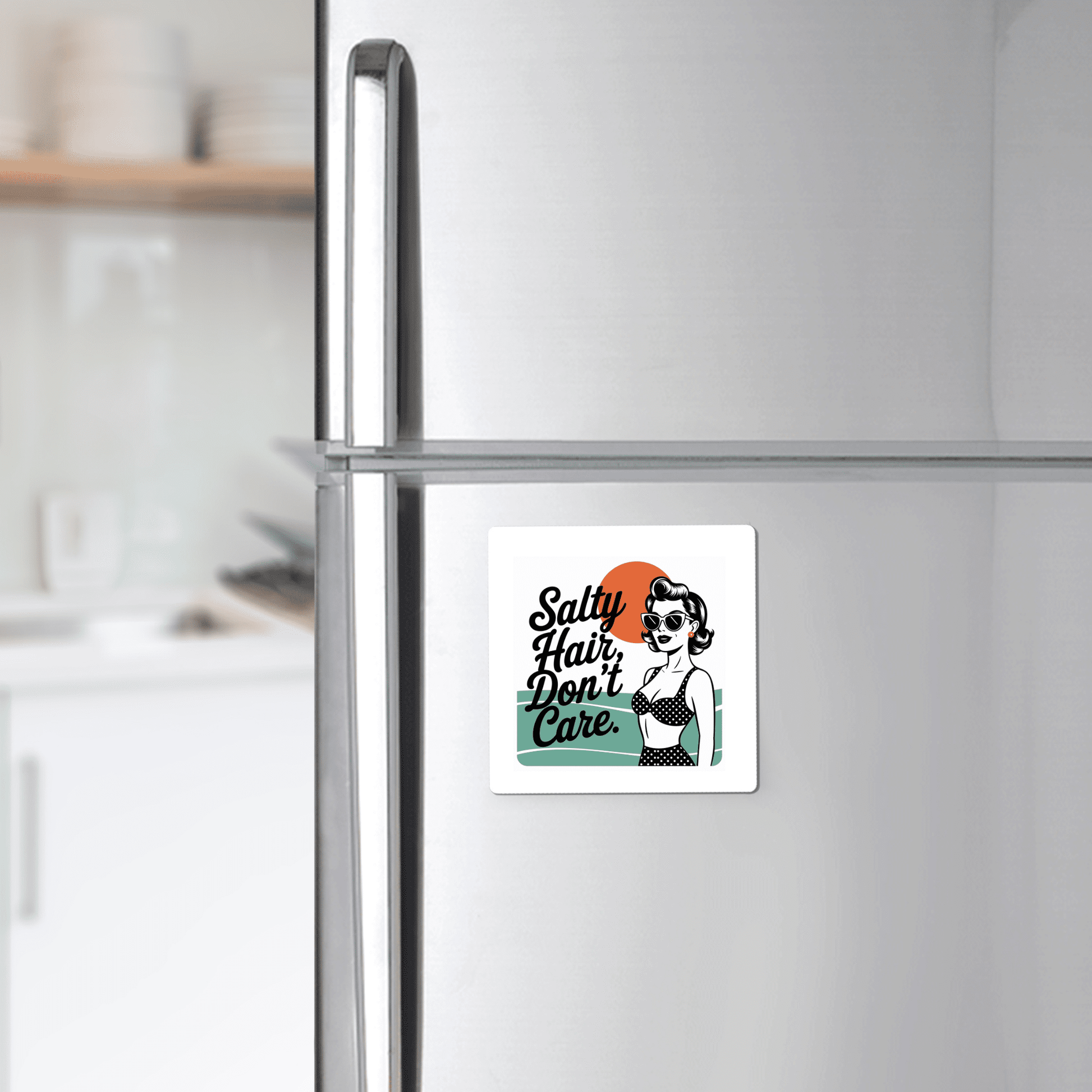 The Mirabilia Boutique "Salty Hair Don’t Care Magnet – Retro Beach Quote" features a stylish woman in sunglasses and swimsuit on an orange and teal background—fun beach house decor. The kitchen is softly blurred in the background.