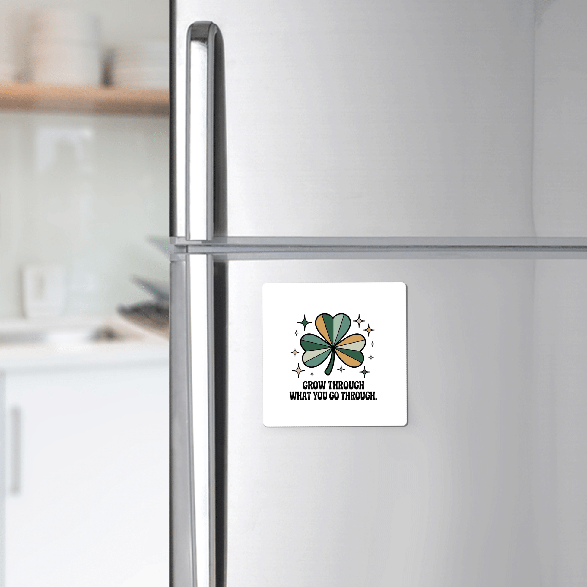 A silver refrigerator displays Mirabilia Boutique’s "Grow Through What You Go Through Magnet," featuring a green and brown four-leaf clover with stars and the motivational text: "Grow through what you go through.