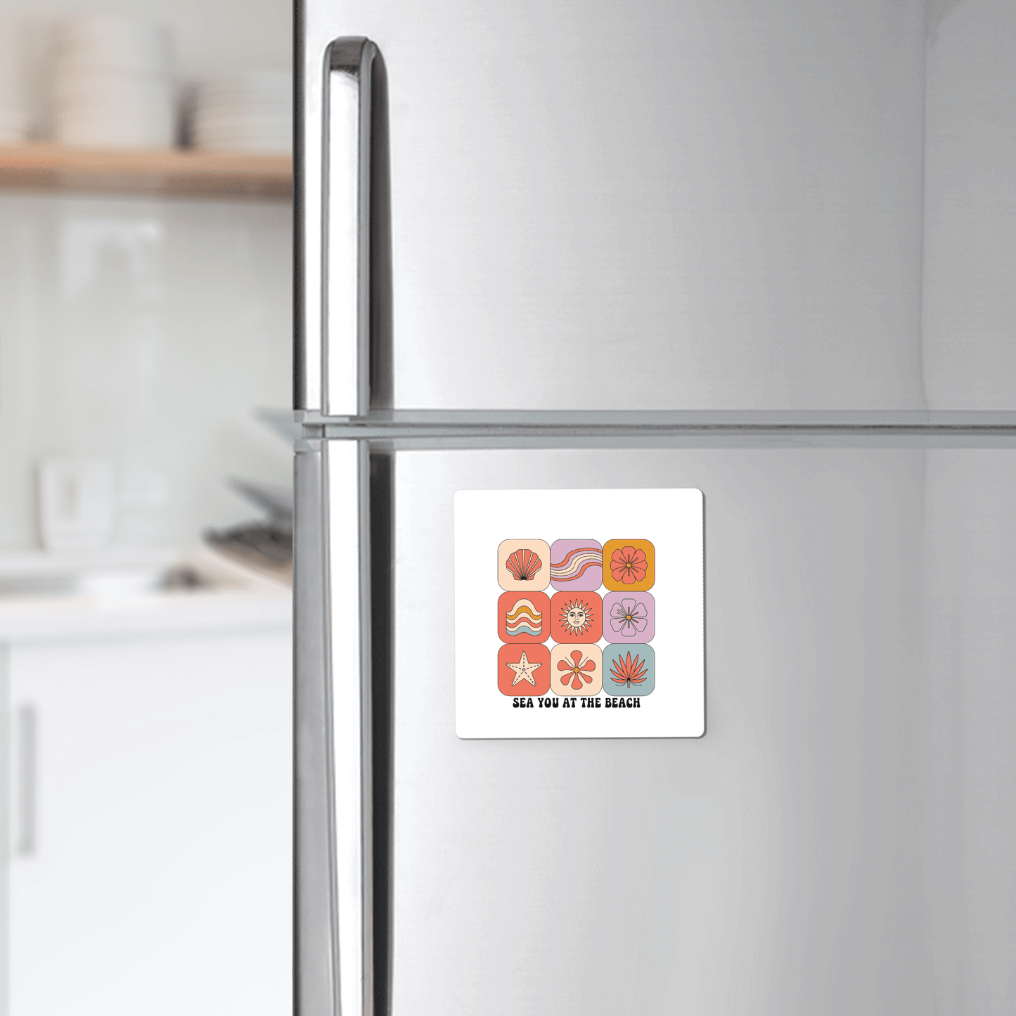 A refrigerator in a kitchen displays the Mirabilia Boutique "Sea You at the Beach Magnet – Retro Summer Vibes," a square magnet with colorful beach icons and the phrase "SEA YOU AT THE BEACH," adding coastal decor flair.