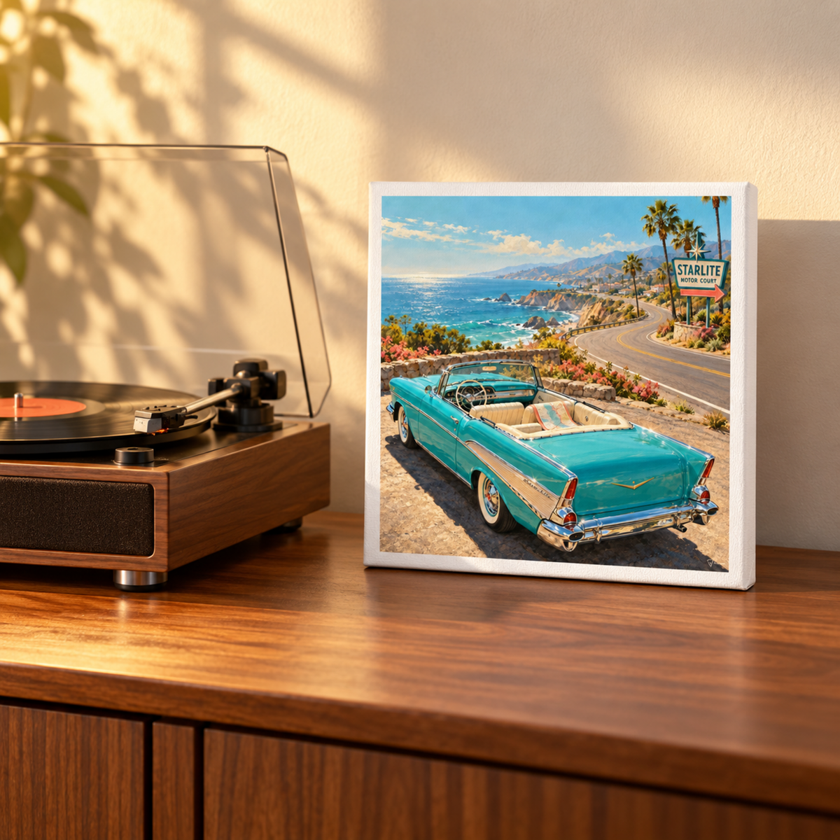 The Road Opens Canvas | Chrome & Starlight displayed on a wooden surface next to a record player, featuring a turquoise convertible on a coastal road near a Starlite Motor Court sign.