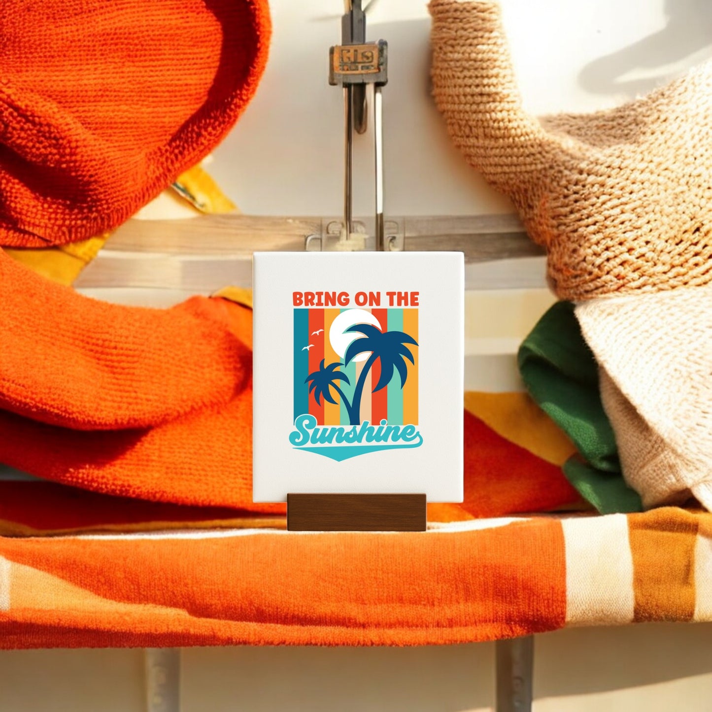 The Bring on the Sunshine Canvas – Retro Palm Tree Art by Mirabilia Boutique features a sunset, palm trees, and birds on a mini canvas with easel. Pair it with orange, cream, and green towels or blankets for perfect beachy accents.