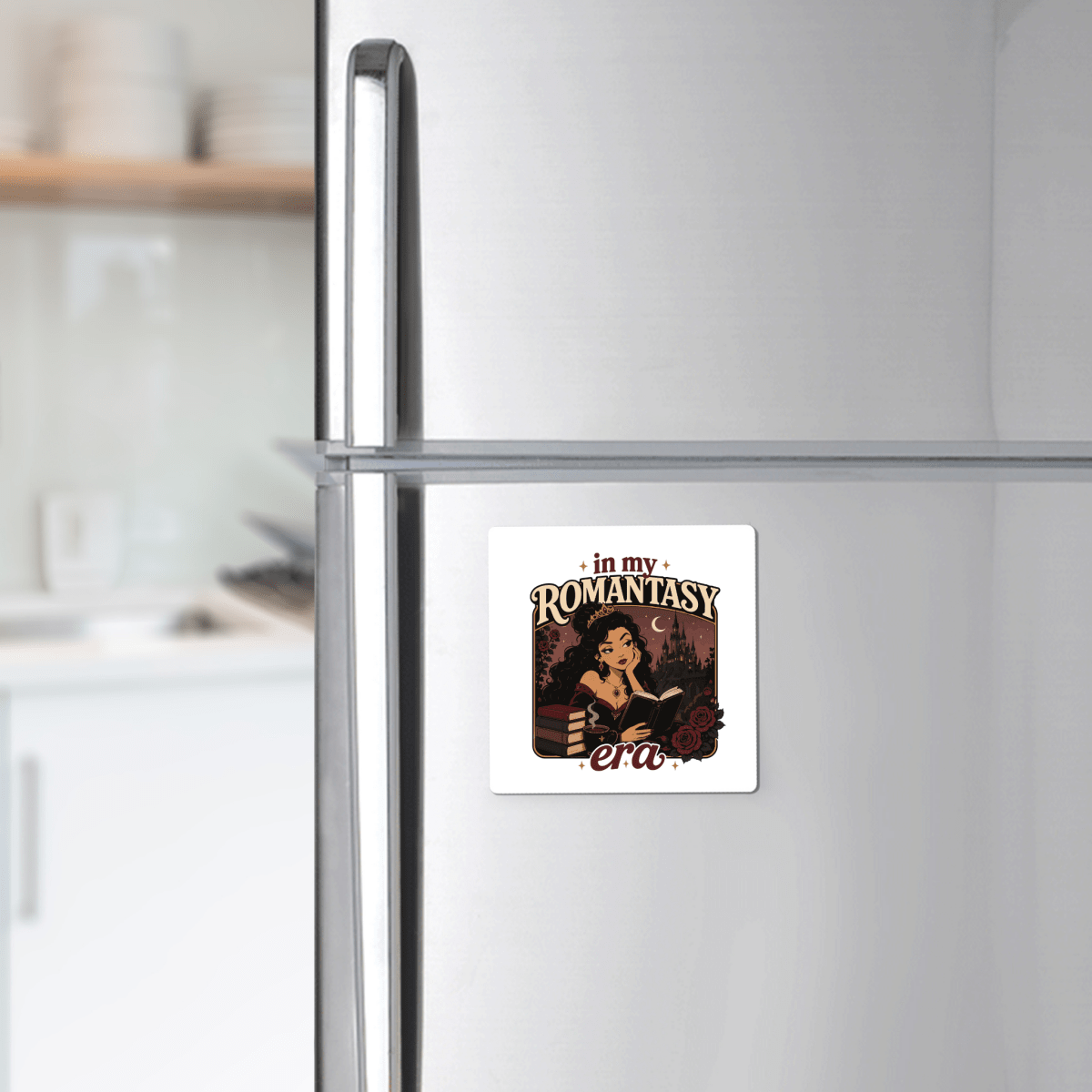 The Mirabilia Boutique "In My Romantasy Era Magnet" is a square refrigerator magnet featuring an illustrated woman reading amidst fantasy elements and the phrase "in my ROMANTASY era"—a delightful bookish accessory and perfect gift for any fantasy reader.