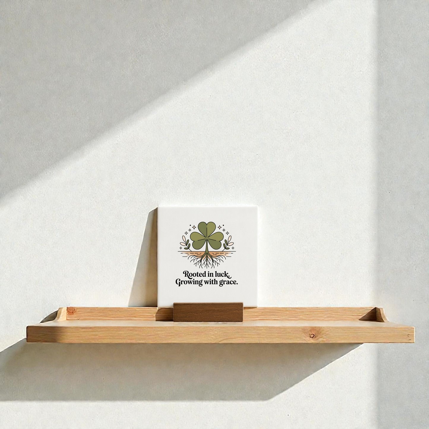 The Mirabilia Boutique "Rooted in Luck, Growing with Grace" 4x4 canvas sign, featuring a green four-leaf clover, adds charming encouragement to any space and makes a thoughtful gift. Sunlight softly highlights its lovely design.