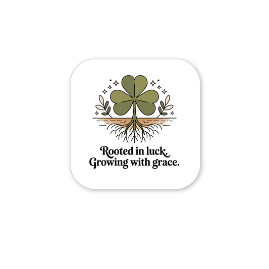 The Rooted in Luck Shamrock Magnet by Mirabilia Boutique features a green four-leaf clover with roots, small plants, and sparkles above "Rooted in luck. Growing with grace."—an Irish-inspired accent for your fridge.