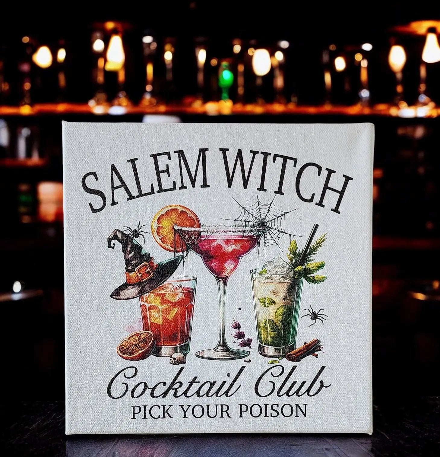 The "Salem Witch Cocktail Club" sign by Mirabilia Boutique features three enchanting witch-themed cocktails, each adorned with a witch hat, citrus slices, and spiders. Its background of blurred bar lights perfectly captures the Halloween spirit, infusing the scene with an eerie charm.