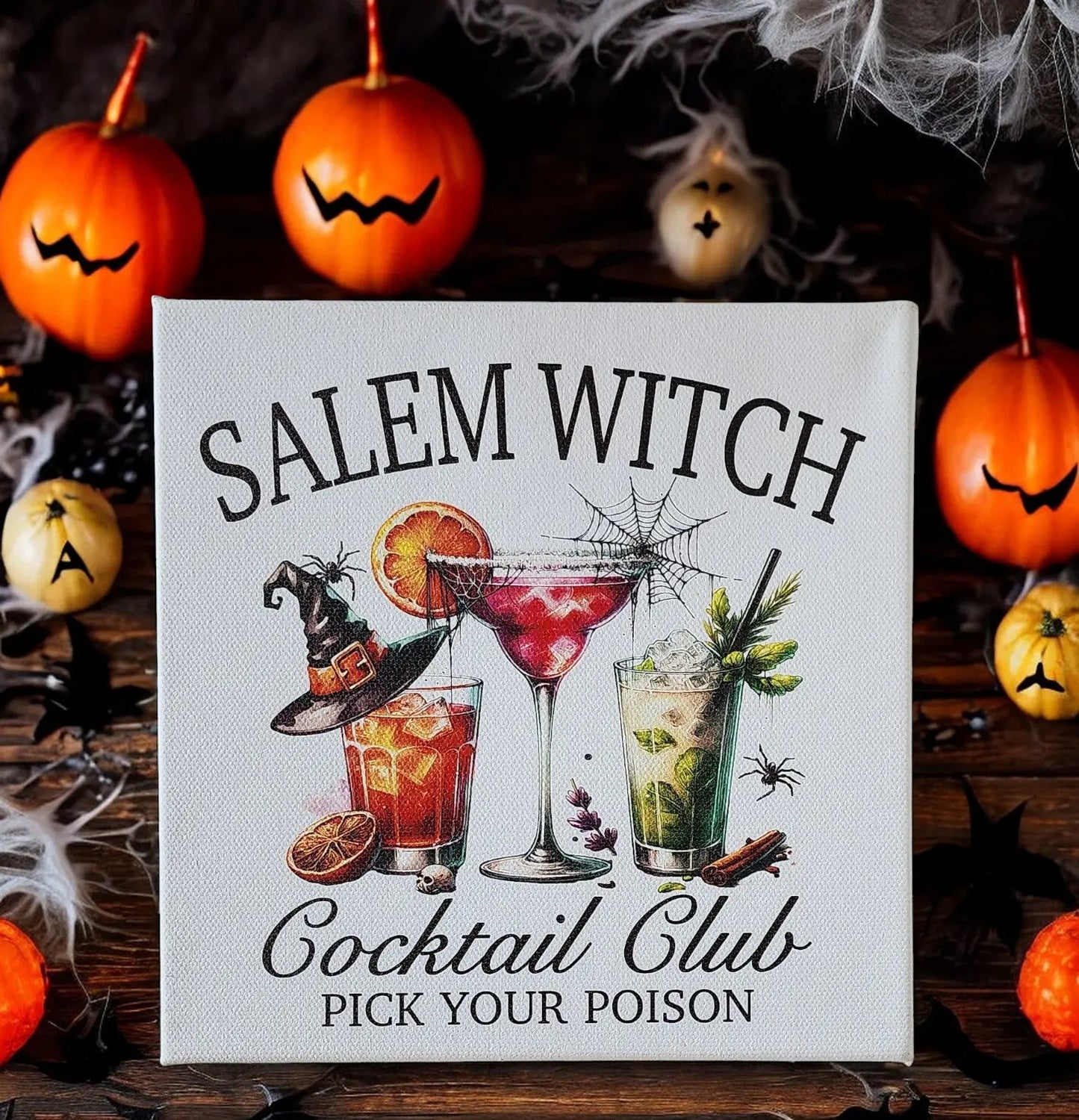 The Salem Witch Cocktail Club Sign from Mirabilia Boutique captures the Halloween spirit with its "Pick Your Poison" theme, showcasing witchy cocktails such as martinis, whiskey drinks, and mojitos. These beverages are creatively adorned with spiders and witch hats, all set against a backdrop of Jack-o'-lanterns and cobwebs for an extra spooky touch.