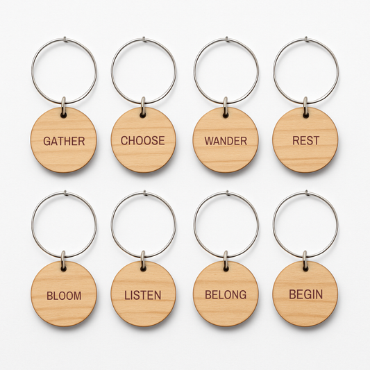 Sand & Saffron Wine Charms set of 8: eight circular wooden wine charms, each hanging from a silver hoop and engraved with a different word: Gather, Choose, Wander, Rest, Bloom, Listen, Belong, and Begin.