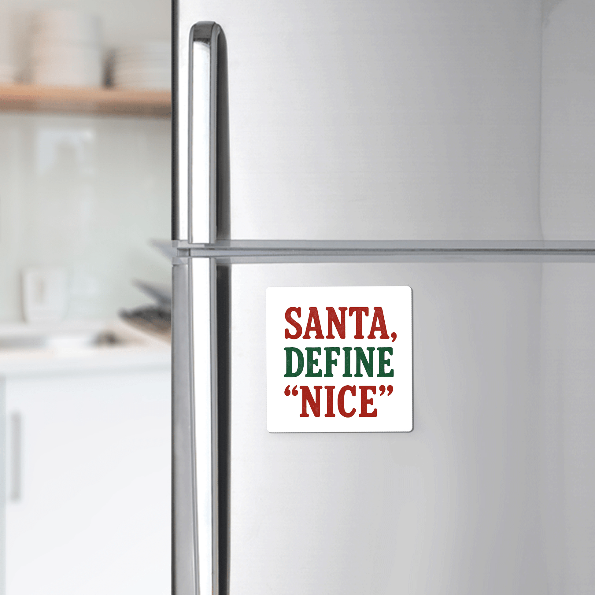 A Mirabilia Boutique "Santa Define Nice" magnet—featuring bold red and green text—is a funny Christmas fridge gift, perfect as a stocking stuffer or holiday gag from their collection. The softly blurred kitchen adds festive charm.