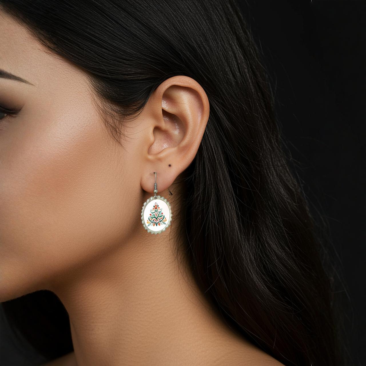 A woman with long dark hair wears Mirabilia Boutique's Scandi Christmas Tree Earrings, Nordic-inspired holiday jewelry with a colorful floral design. The black background highlights the unique accessory and her elegant profile.